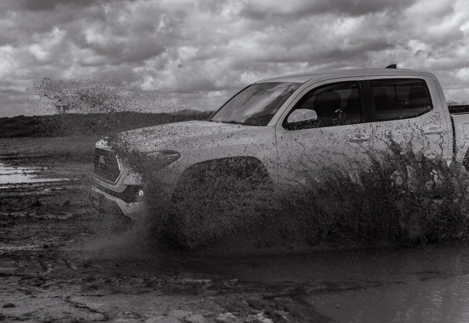 Toyota Tacoma spraying mud as it navigates a trail in 4WD.