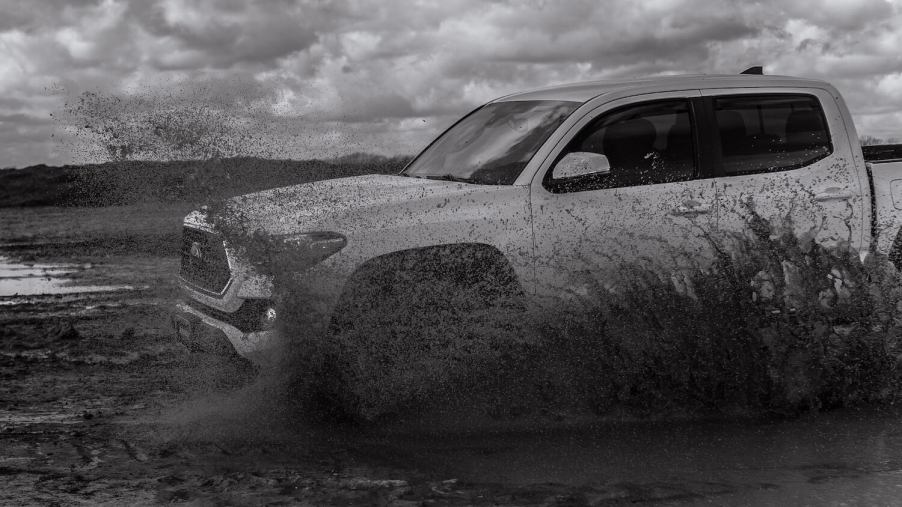 A Toyota Tacoma drives through a muddy field.