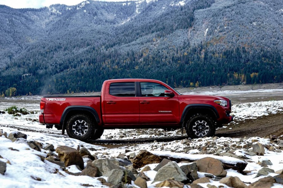 A red four-door Toyota Tacoma pickup truck parked in front of a snowy mountain.
