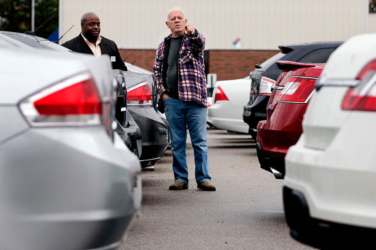 A man and a car salesmen browse used SUVs at a dealership.