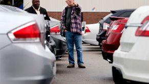 A man and a car salesmen browse used SUVs at a dealership.