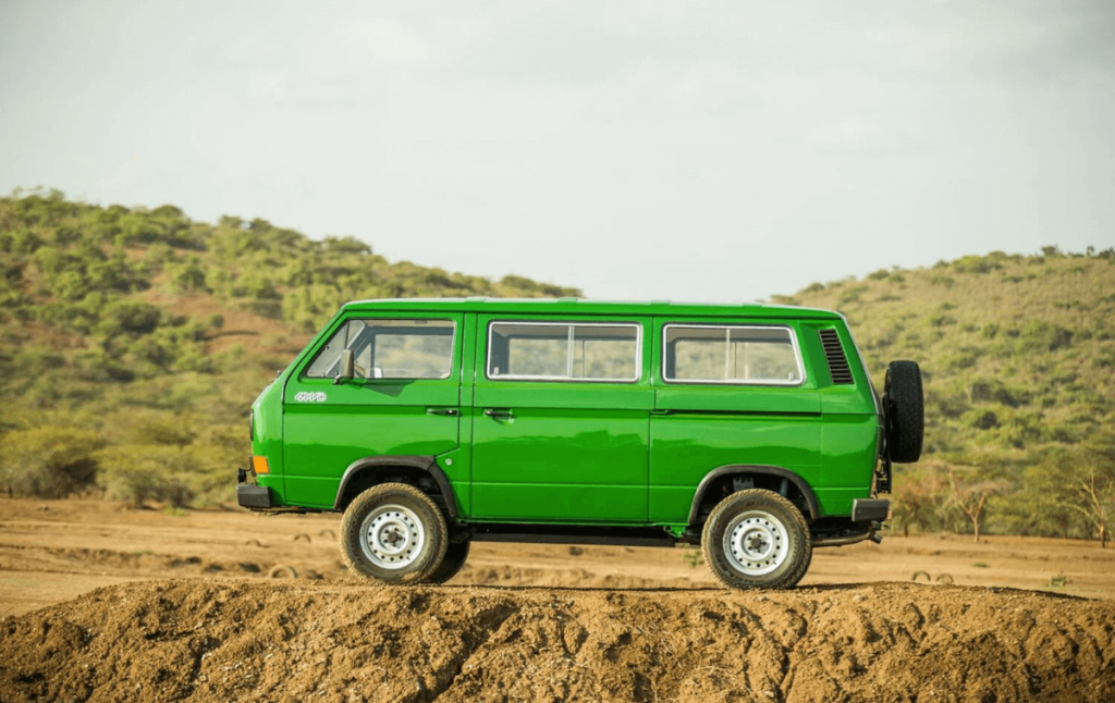 Volkswagen Synchro Van in green parked on top of a hill in Africa. 