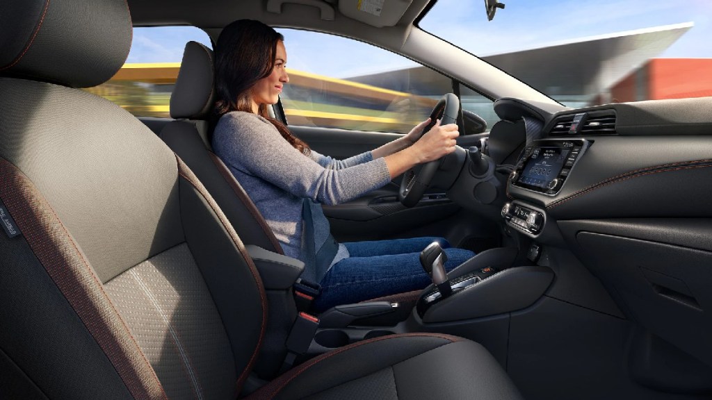Woman driving 2023 Nissan Versa, most affordable new car in 2023, not a Toyota or Honda