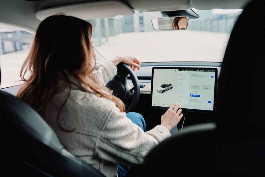 A woman types on the touchscreen of her Tesla vehicle, in front of the cabin camera.