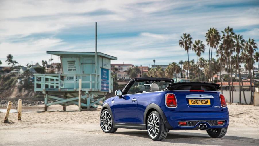 A rear shot of a blue 2019 Mini Convertible compact car model parked on a beach asphalt lot