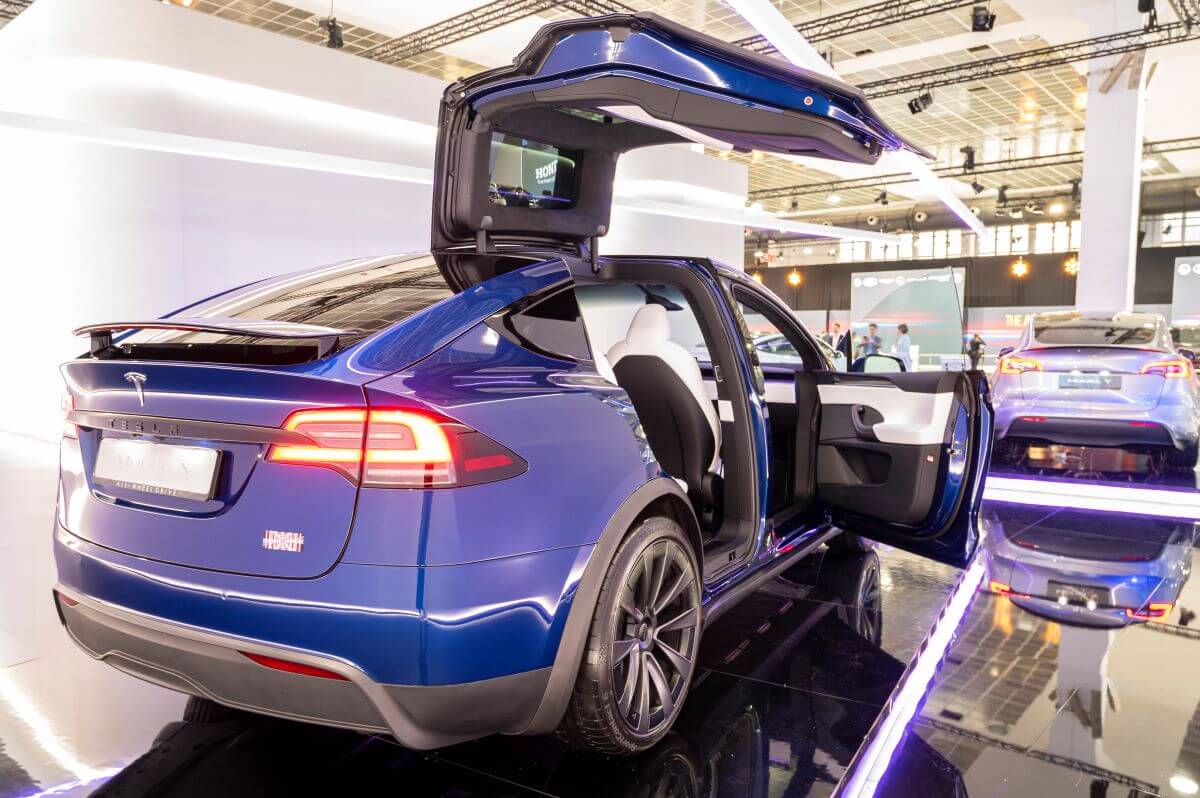 A blue Tesla Model X luxury electric SUV model with its falcon-wing doors open at the Brussels Expo