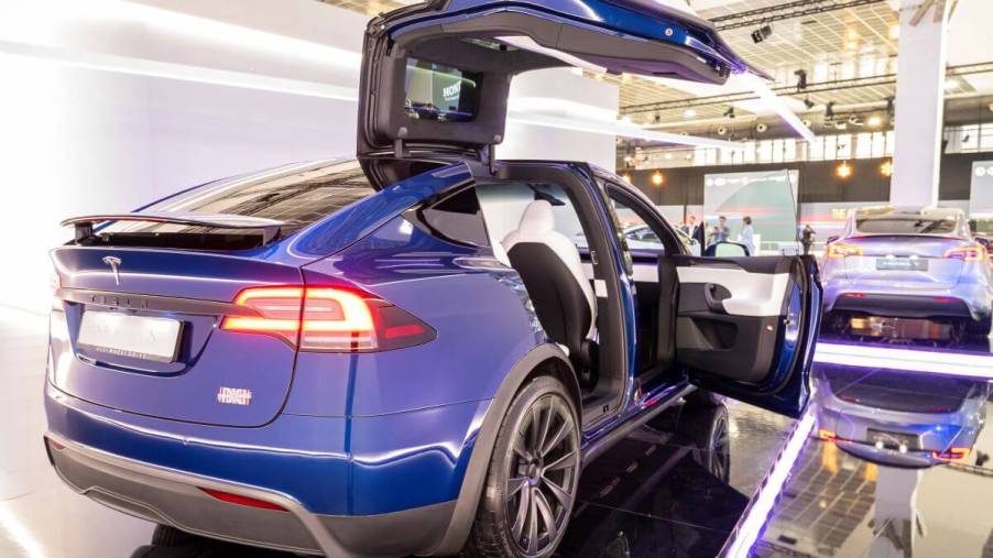 A blue Tesla Model X luxury electric SUV model with its falcon-wing doors open at the Brussels Expo