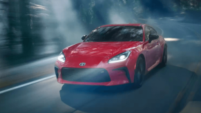 A red 2023 Toyota GR86 sports car fastback coupe model driving through a foggy forest at night