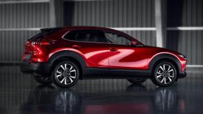 A side profile shot of a red 2023 Mazda CX-30 subcompact crossover SUV model parked in an empty hangar