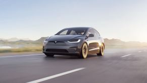 A gray Tesla Model X with incredible resale value driving down a desert road