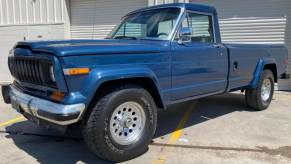 Old Jeep Gladiator pickup truck parked in front of a garage door.