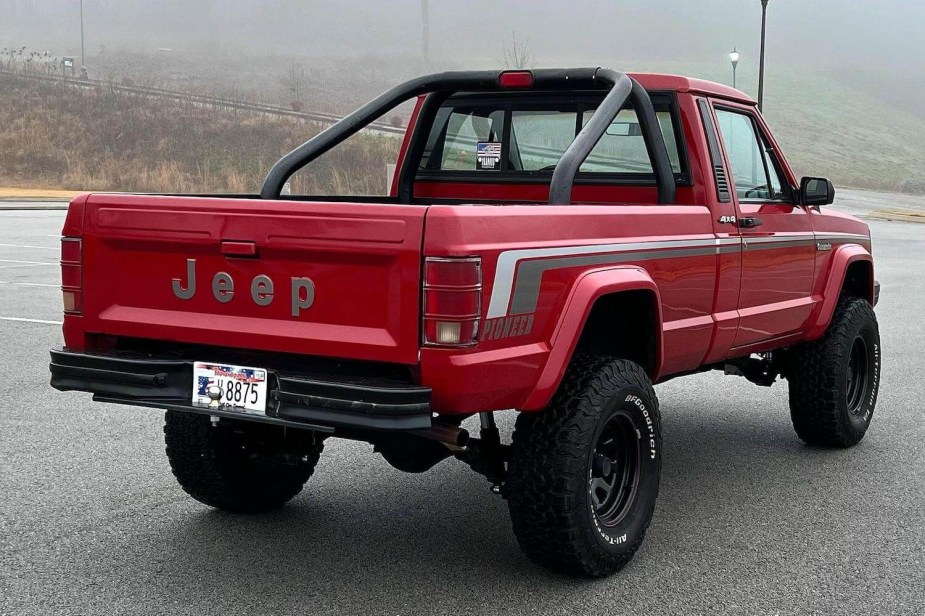 The bed and tailgate of a 1989 Jeep Comanche classic truck in a parking lot, the fog visible in the background.