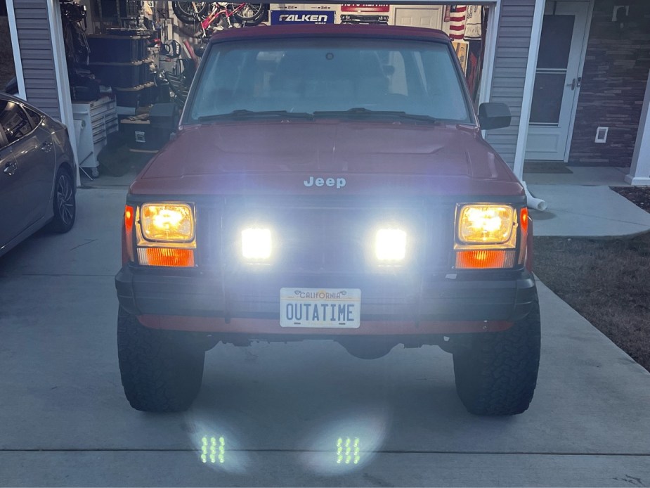 The headlights and trail lights on a classic Jeep Comanche truck, illuminated at night.