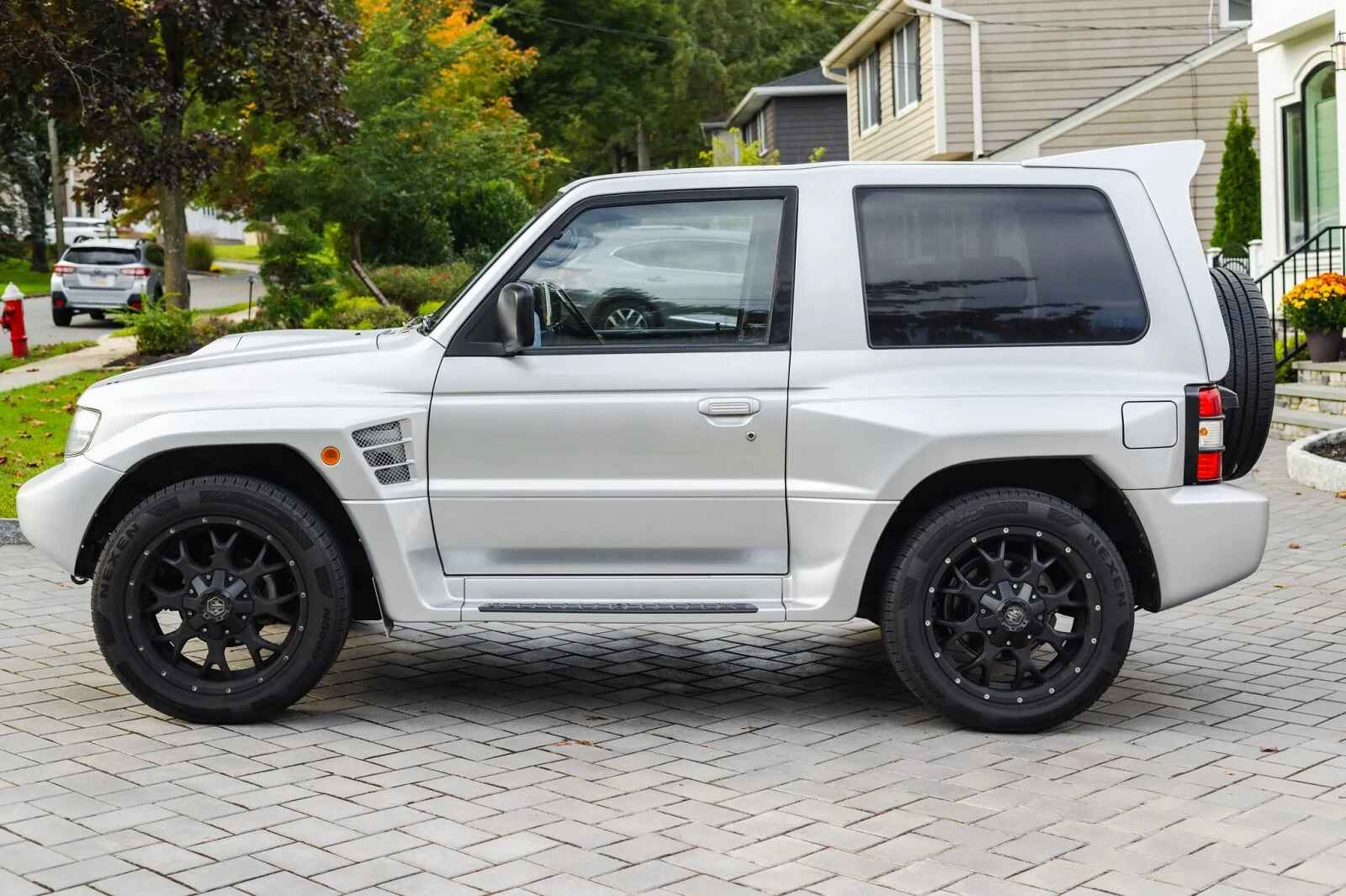 A light metallic 1997 Mitsubishi Pajero Evolution 2-door SUV parked in left profile view