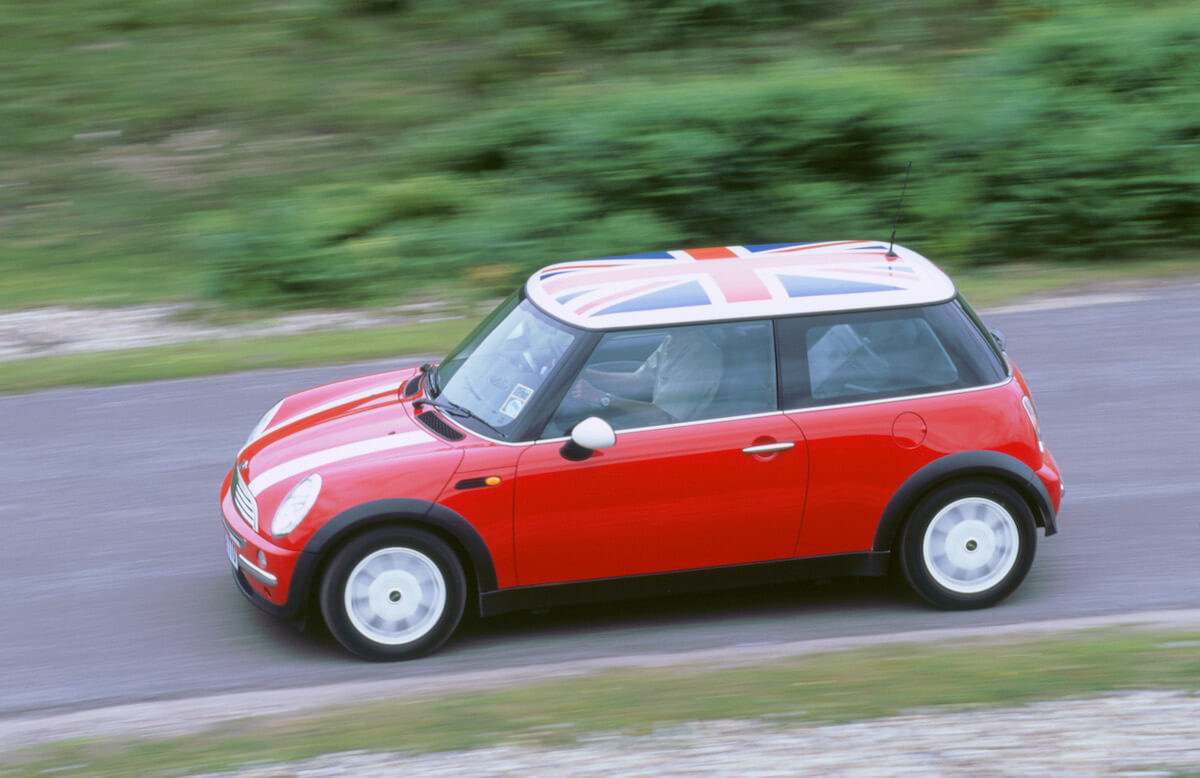 A red 2002 Mini Cooper driving down a side road