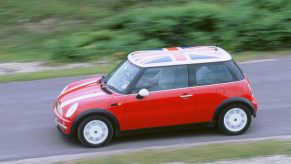 A red 2002 Mini Cooper driving down a side road