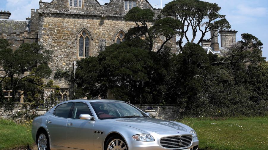 A silver 2004 Maserati Quattroporte parked in front of a castle