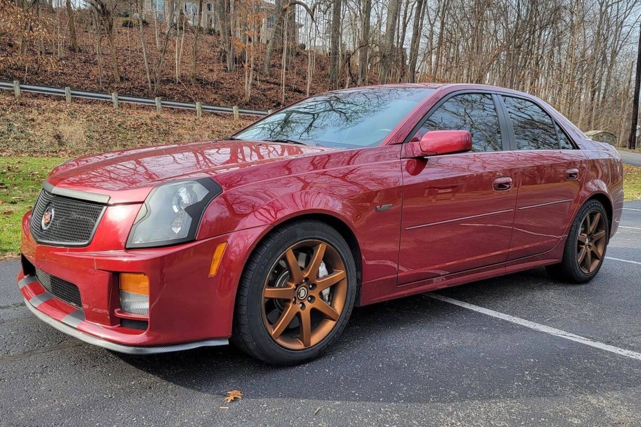 The front of a red Cadillac CTS-V muscle car, woods visible in the background.g