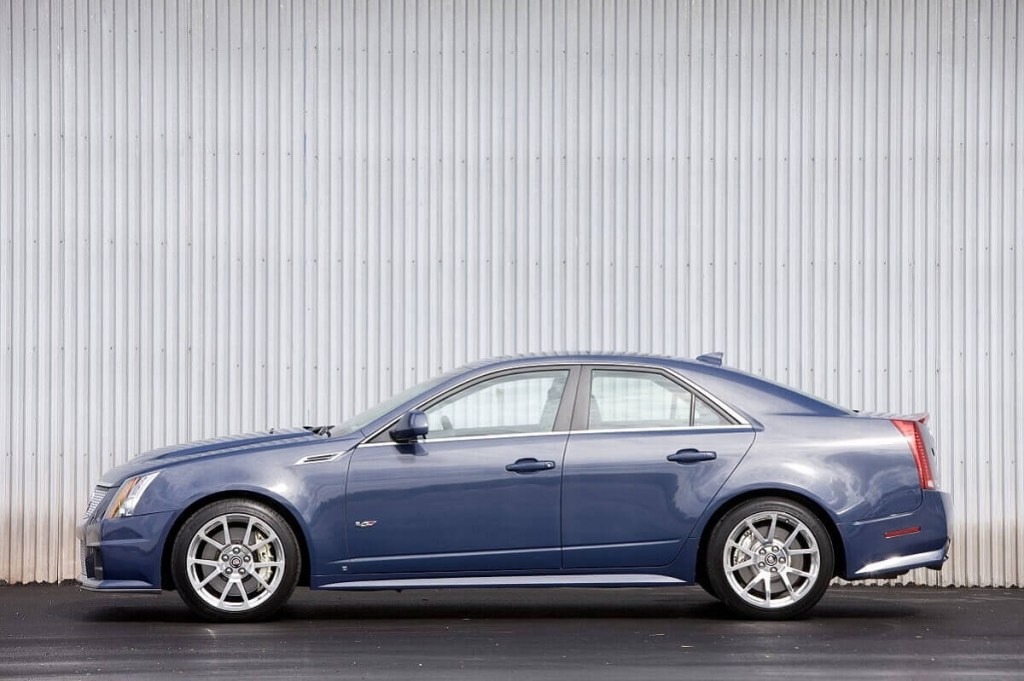 A blue 2009 Cadillac CTS series sedan parks next to a hangar. 