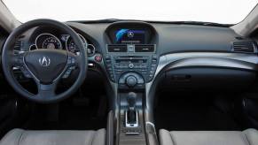 The interior front row seating and dashboard of a 2012 Acura TL executive car model. This model includes one of the more common Acura problems.