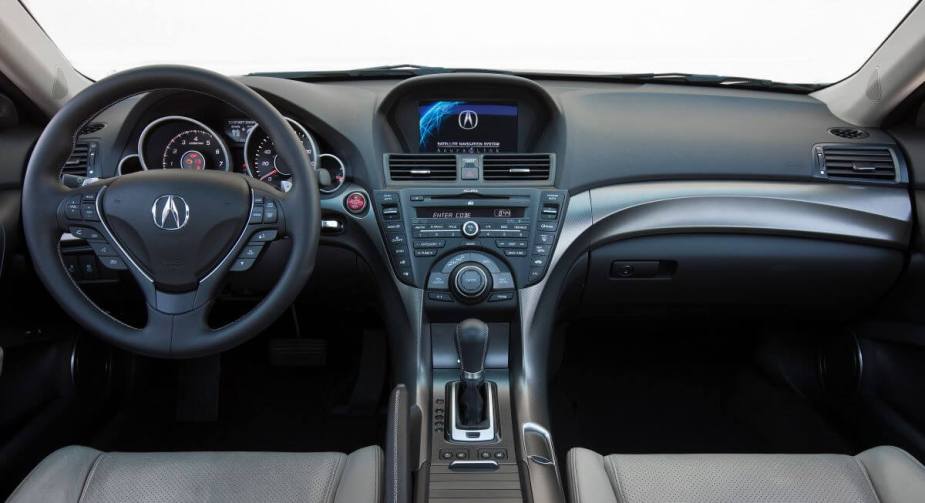 The interior front row seating and dashboard of a 2012 Acura TL executive car model. This model includes one of the more common Acura problems.