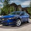 A dark blue 2014 Chevy Impala 2.5L iVLC full-size sedan model parked outside a luxury home