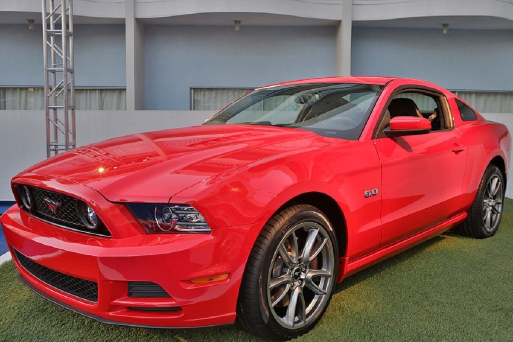 A red 2014 Ford Mustang GT, the cheapest V8 sports car in the model's lineup, flashes 5.0 badges. 