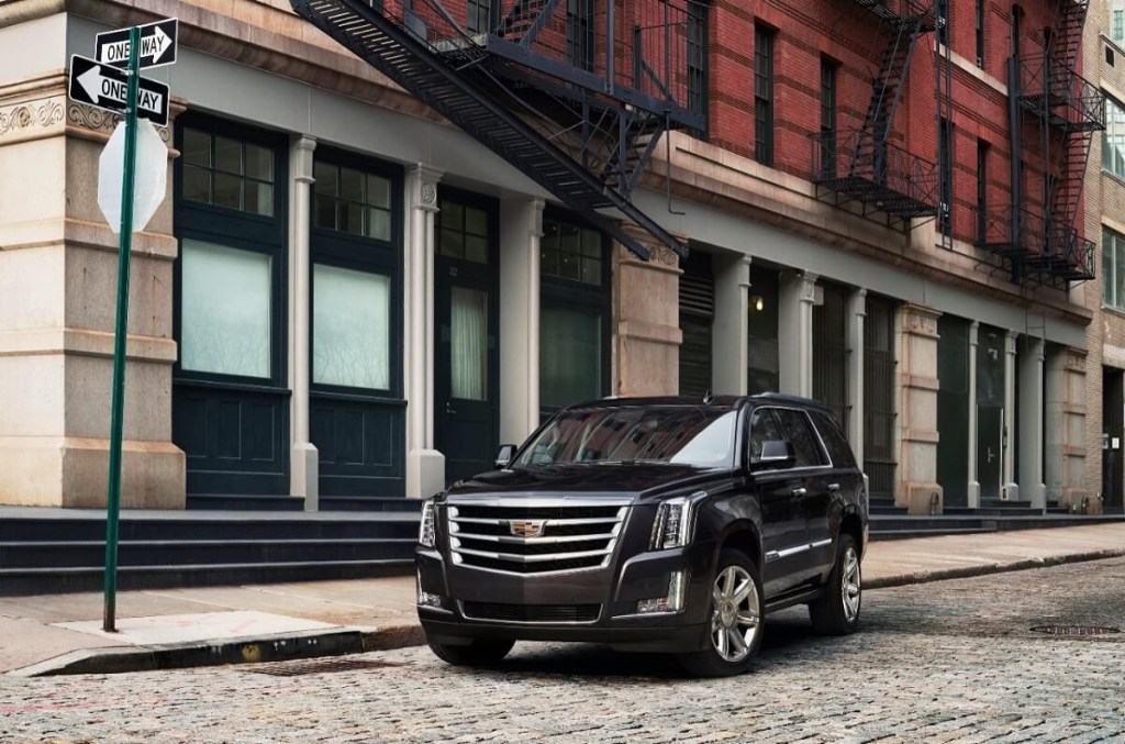 A 2015 to 2017 Cadillac Escalade parks next to a building.