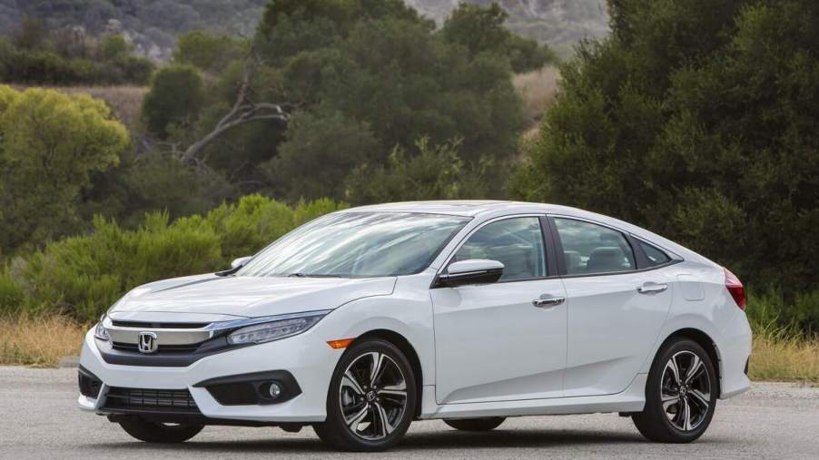A white 2018 Honda Civic Sedan parked in front of trees and hills