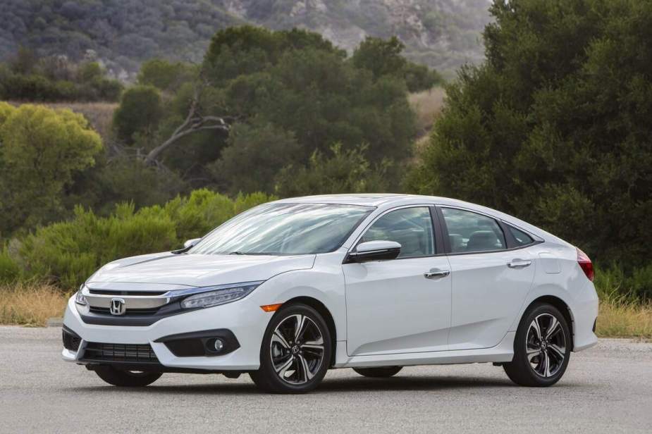 A white 2018 Honda Civic Sedan parked in front of trees and hills