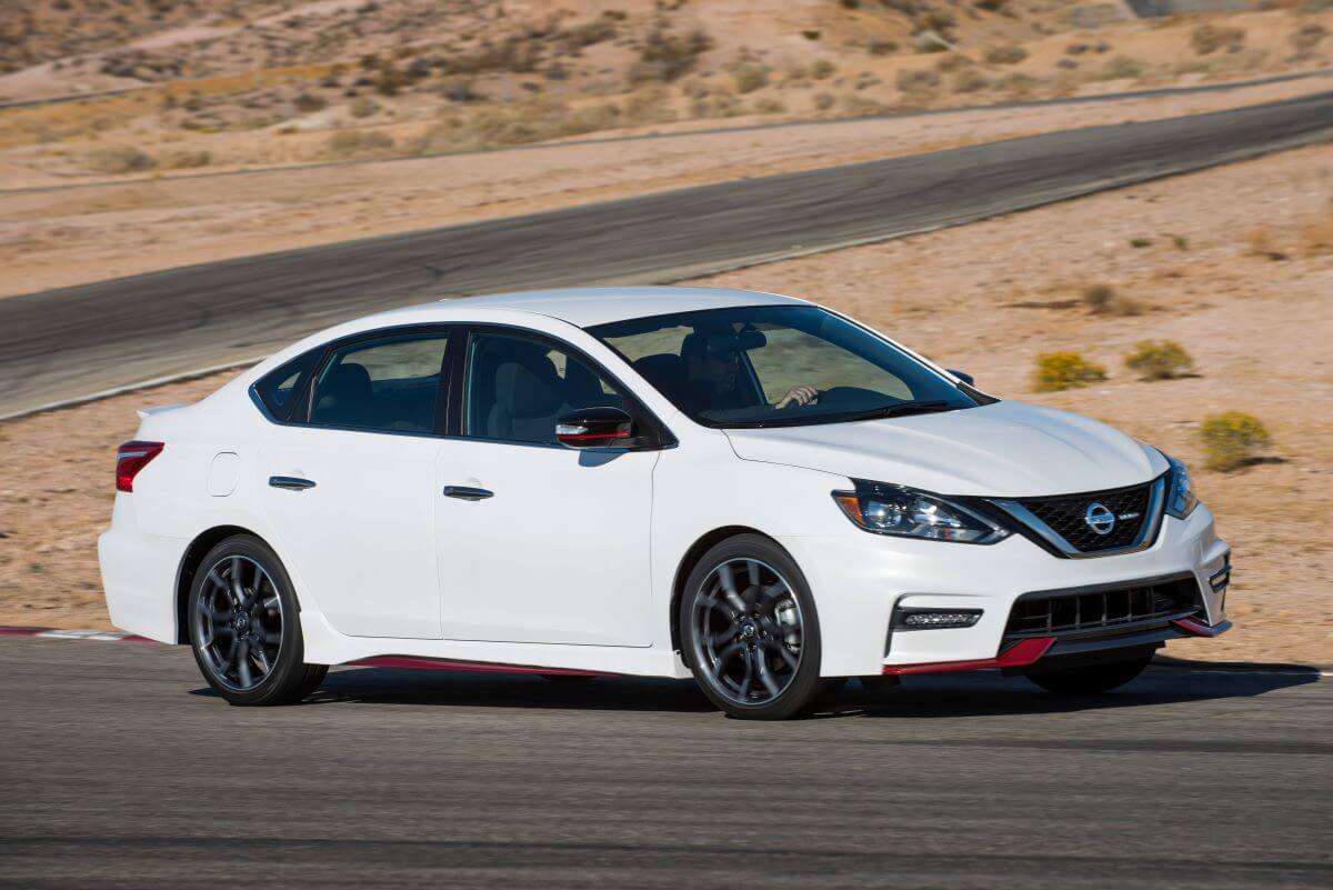 A white 2018 Nissan Sentra NISMO compact sedan model with a performance style package on a desert road