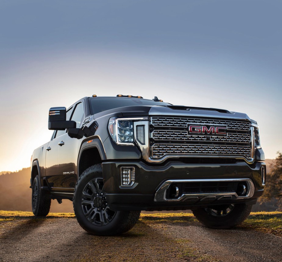 The grille of a black GMC Sierra parked in front of a setting sun.
