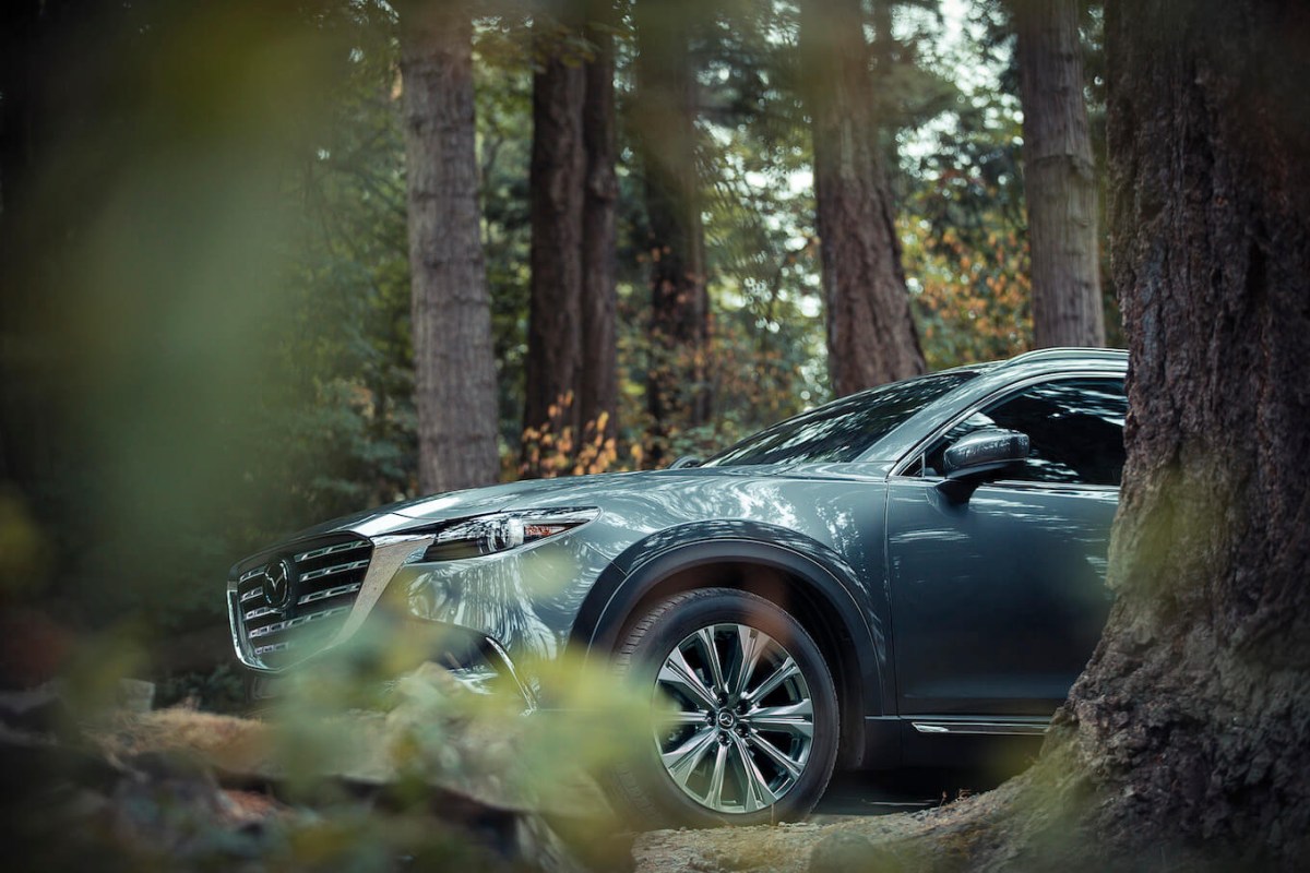 A green Mazda CX-9 parked in the woods.