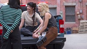 Three people sitting in the bed of a Ford Maverick.