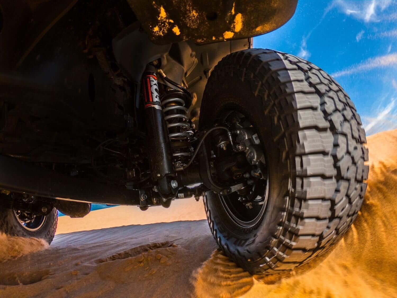 Closeup of the suspension of American-made Jeep Gladiator midsize pickup truck navigating Mojave sand dunes.