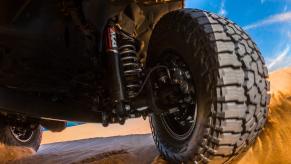 Closeup of the suspension of American-made Jeep Gladiator midsize pickup truck navigating Mojave sand dunes.