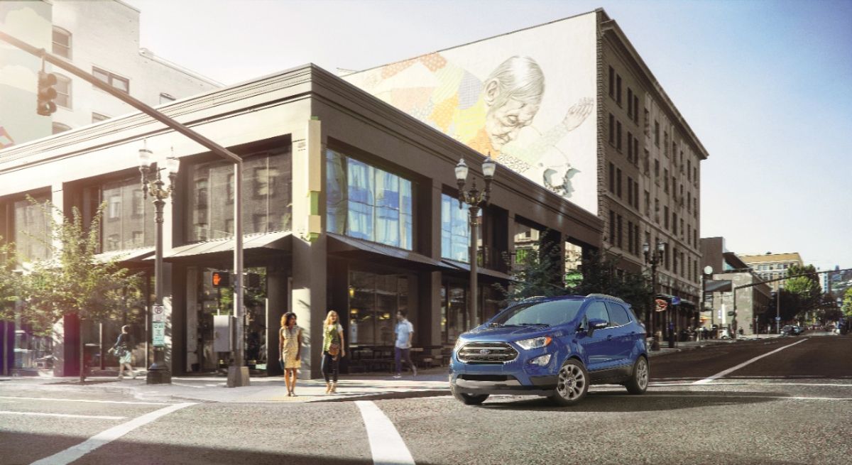 A blue 2022 Ford EcoSport driving in a city.