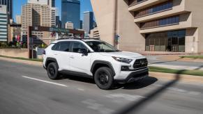 A white 2023 Toyota RAV4 TRD Off-Road driving on a city road