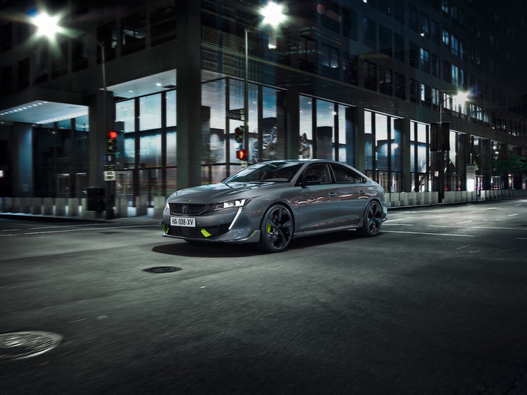 A dark gray 2023 508 Peugeot Sport driving downtown in the city