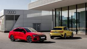 A red 2023 Audi S3 parked in front of another yellow Audi model in front of a building