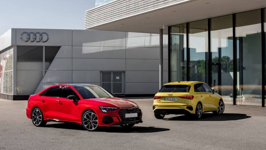 A red 2023 Audi S3 parked in front of another yellow Audi model in front of a building