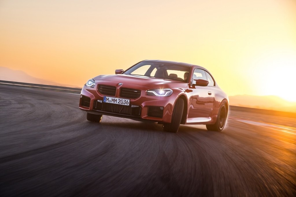 A red 2023 BMW M2 with a manual transmission scorches its tires. 