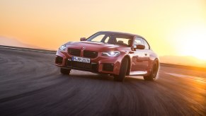 A red 2023 BMW M2 with a manual transmission scorches its tires.