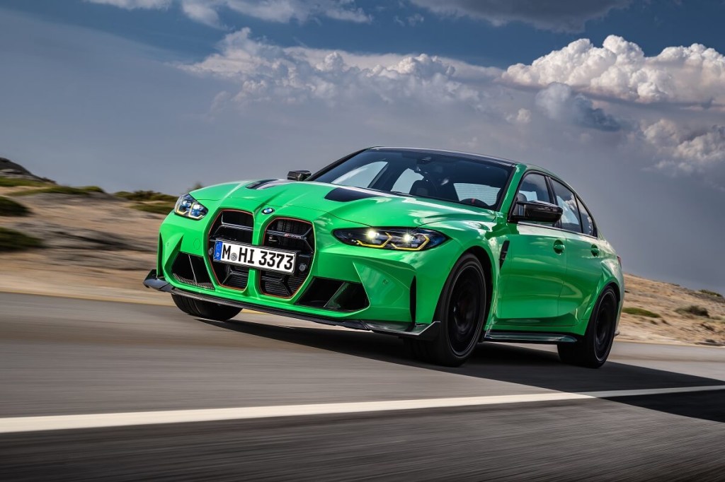 A green BMW M3 performance car blasts down a straight on a track.