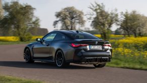 A matte black 2023 BMW M4 with a manual transmission drives country roads.