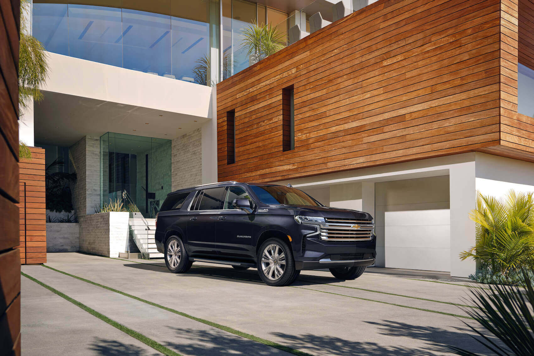 The 2023 Chevy Suburban, the biggest 2023 SUVs, in black parked in front of a modern building with wood accents.