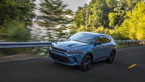A blue 2023 Dodge Hornet GT drives quickly with green trees in the background.