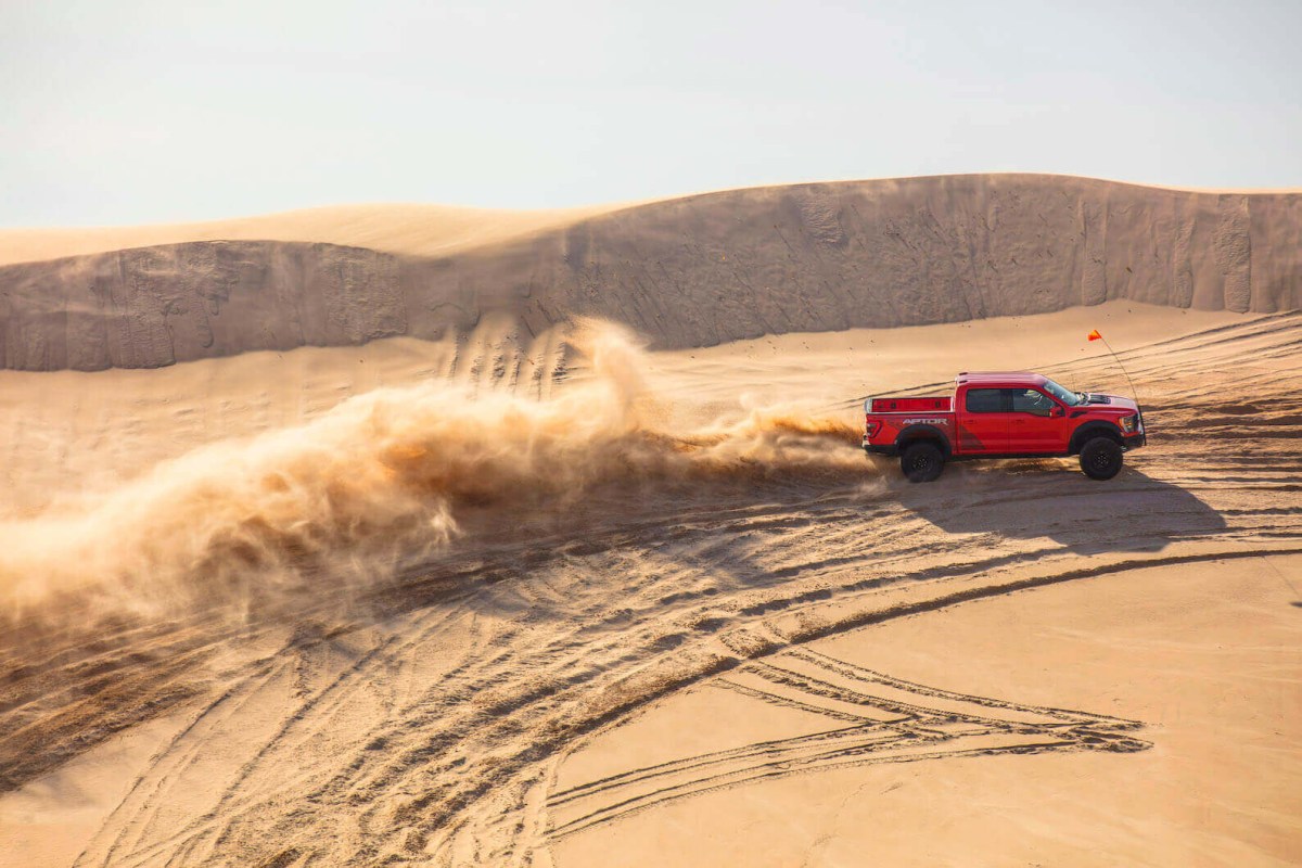 A red 2023 Ford F-150 Raptor in the middle of the desert.