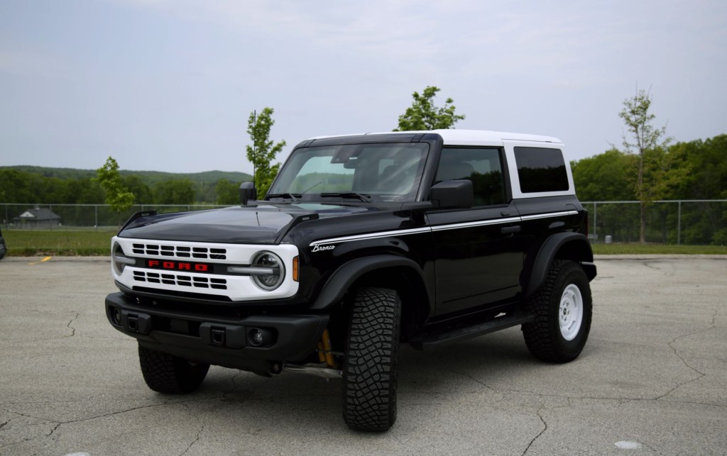 A black 2023 Ford Bronco Heritage Edition sits in front of green hills.