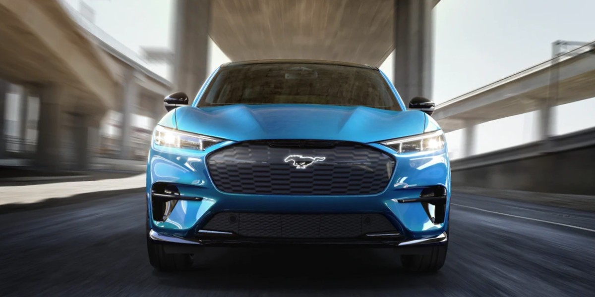 A blue 2023 Ford Mustang Mach-E small electric SUV is driving.